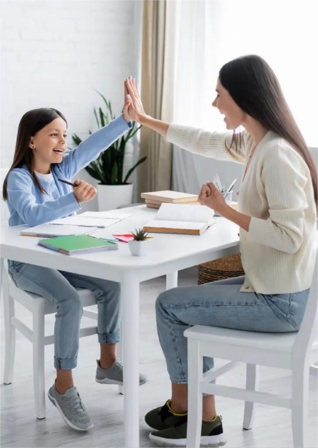 A parent and child sharing a high-five over homework at the kitchen table